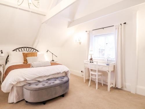 a white bedroom with a bed and a desk at Tower End Cottage in Woodbridge