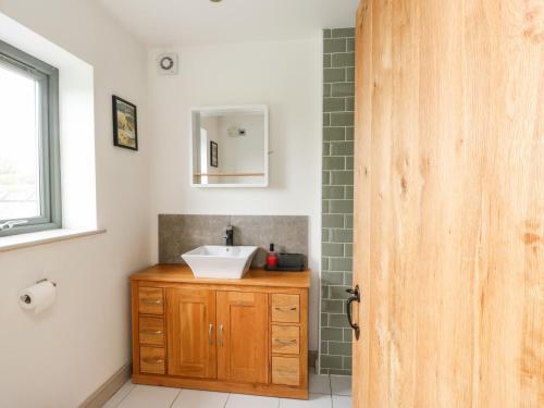uma casa de banho com um lavatório e uma porta de madeira em Cae Du em Llanfairpwllgwyngyll