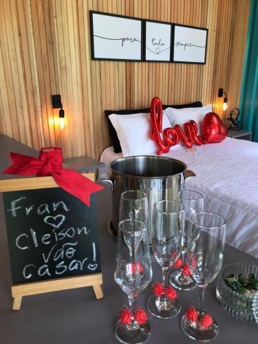a room with a bed with wine glasses and a sign at Pousada Sitio Raizes in Siderópolis
