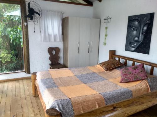 a bedroom with a bed with a checkered blanket at Pousada Morgana, Praia do Rosa in Praia do Rosa
