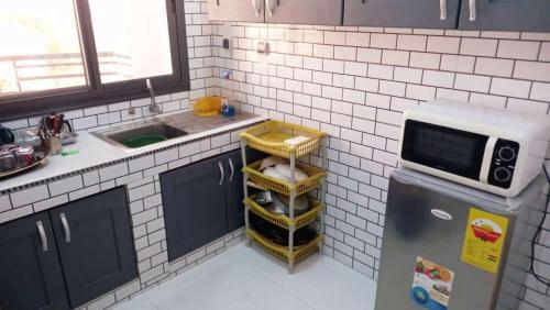 a small kitchen with a microwave and a refrigerator at Résidence La Digue Cité Vauvert in Saint-Louis