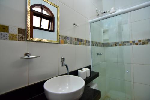 ein Bad mit einem Waschbecken und einer Glasdusche in der Unterkunft FLAT Estalagem 11 in Arraial do Cabo