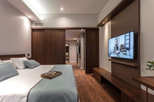 um quarto com uma cama grande e uma televisão de ecrã plano em Huinid Obelisco Hotel em Buenos Aires