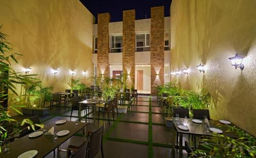ein Restaurant mit Tischen, Stühlen und Pflanzen in der Unterkunft Hotel Shlok- Pure Veg , Kolhapur in Kolhapur