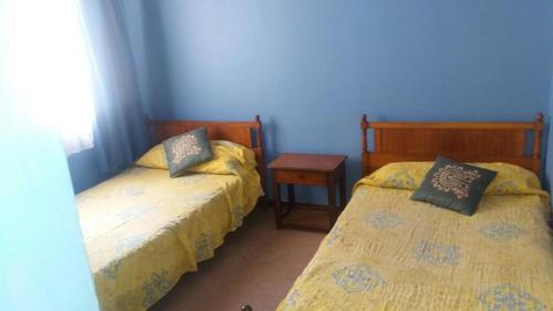 1 dormitorio con 2 camas, mesa y pared azul en Casa Norma santiago 8 personas en Santiago