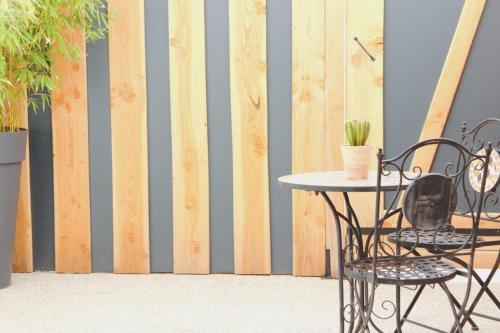 a table and chairs in front of a wooden wall at Vanadis, Suites d'exceptions & spa - LE BALNEO in Pacy-sur-Eure