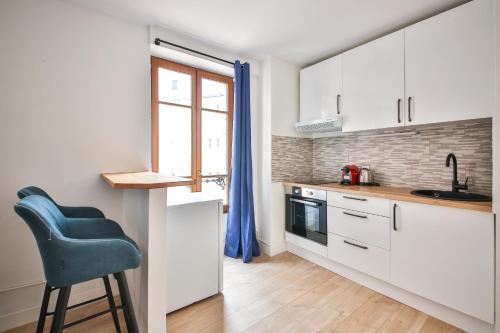 une cuisine avec des placards blancs et une chaise bleue dans l'établissement 32#Studio 2Pers#Sèvres-Lecourbe#Necker, à Paris
