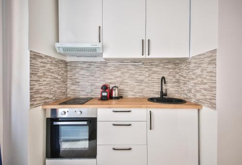 une cuisine avec des armoires blanches et un évier dans l'établissement 32#Studio 2Pers#Sèvres-Lecourbe#Necker, à Paris