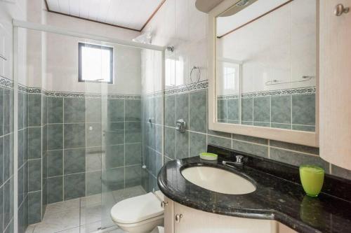 a bathroom with a sink and a toilet and a mirror at Itapema Beira Mar in Itapema