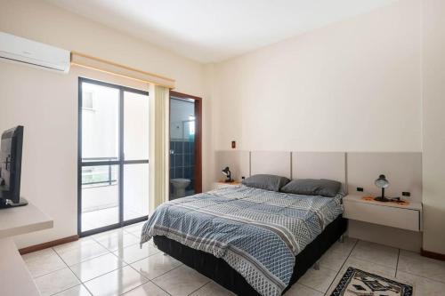 a bedroom with a bed and a sliding glass door at Itapema Beira Mar in Itapema