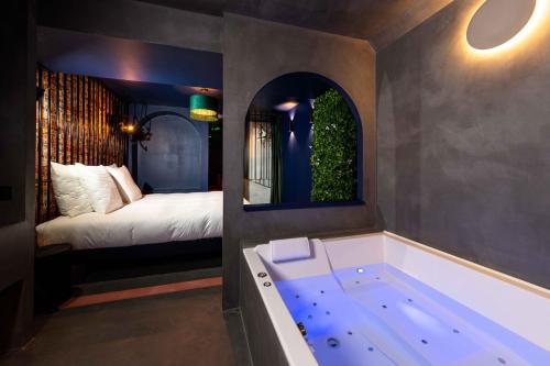 a bathroom with a tub and a bed in a room at Minamina, chambre avec jacuzzi privatif in Roquefort-la-Bédoule