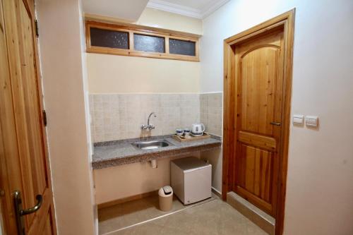 a small bathroom with a sink and a wooden door at Atlantica Ifri Surf Suites in Tamraght Oufella