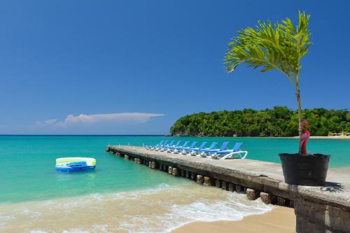 a pier with chairs and a palm tree on a beach at Sand and Tan Beach Hotel in Ocho Rios