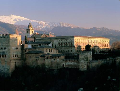 a large building with a clock tower in front of mountains at Hotel Boutique Cerro del Sol Adults only recommended in Granada