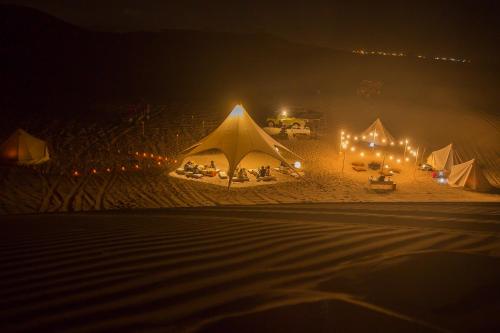 a group of tents on a beach at night at Duna Camp Huacachina in Ica