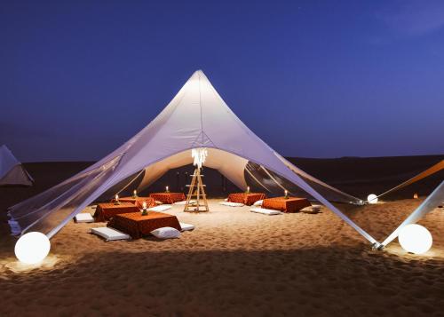 a tent on the beach at night with chairs and tables at Duna Camp Huacachina in Ica