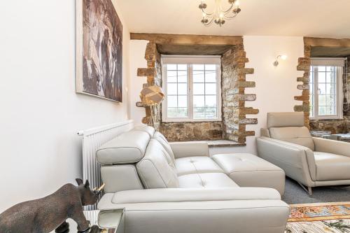 a living room with a white couch and chairs at Bridge End Mill by Guestz in Settle