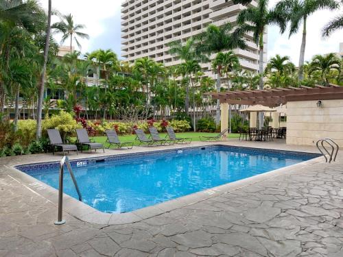 a swimming pool with chairs and a building at Vacation Rental Studios at Royal Garden Waikiki in Honolulu