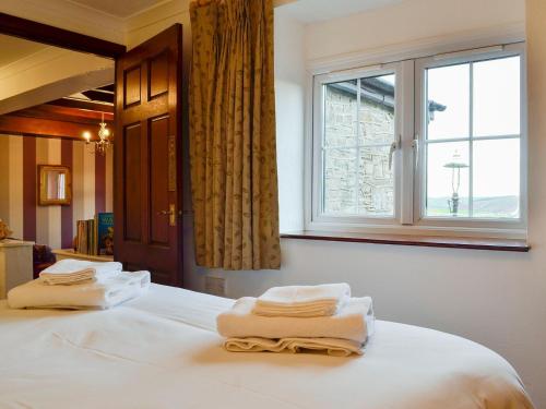 a bedroom with two towels on a bed with a window at Penny Croft - Uk10449 in Llangeinor