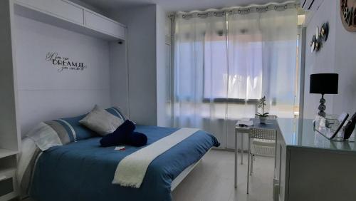 1 dormitorio con cama azul y escritorio en Estudio Torremolinos Centro by AVA Apartments Wifi y Smart TV, en Torremolinos