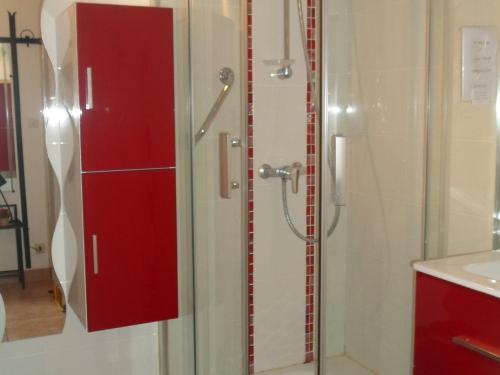 La salle de bains est pourvue d'une douche et d'une armoire rouge. dans l'établissement Mini-studio climatisé proche des Thermes de Balaruc-les-Bains, avec wifi et parking - FR-1-503-107, à Balaruc-les-Bains