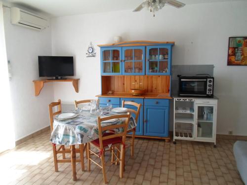 une cuisine avec une table, des chaises et un meuble bleu dans l'établissement Appartement au Bord de l'Étang à Balaruc-les-Bains - Résidence Sécurisée, Climatisé, Pet-Friendly - FR-1-503-122, à Balaruc-les-Bains