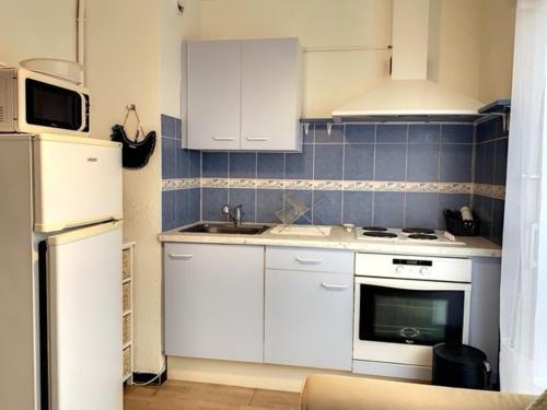 une cuisine avec des armoires blanches, un évier et un réfrigérateur dans l'établissement Studio proche des thermes, bien équipé, animaux admis, stationnement à proximité - FR-1-503-124, à Balaruc-les-Bains