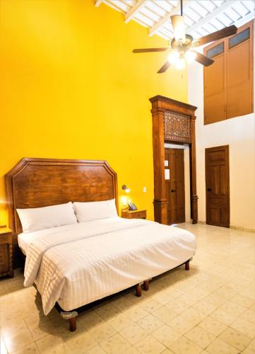 a bedroom with a large bed with a yellow wall at Hotel Real Toledo by Kavia in Mérida