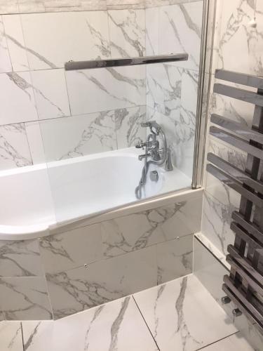 a bathroom with a sink and a marble wall at Devons Unique Short Stay in London