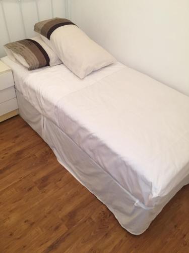 Devons Unique Short Stay في لندن: سرير ذو أغطية ووسائد بيضاء