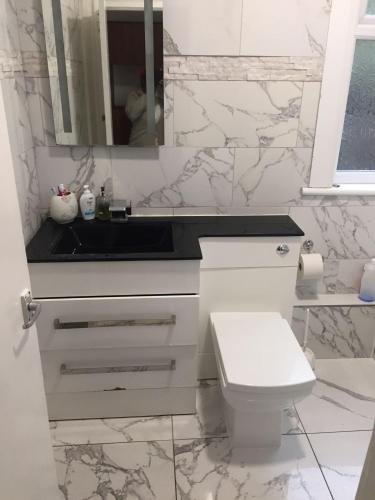 a white bathroom with a sink and a toilet at Devons Unique Short Stay in London