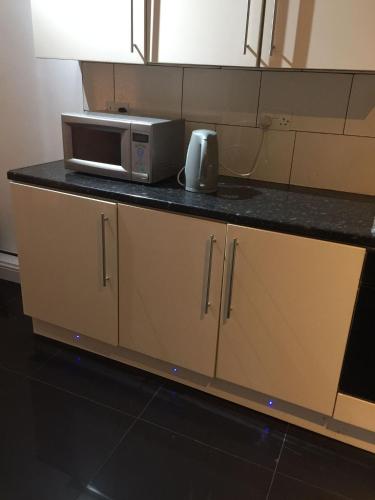 a kitchen counter with a microwave on top of it at Devons Unique Short Stay in London