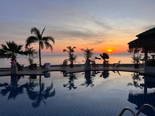 a resort swimming pool with a sunset in the background at Sense Asia in Haad Tian