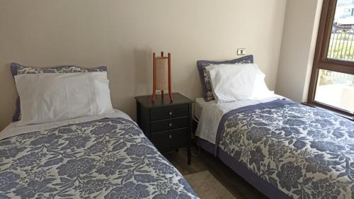 a bedroom with two beds and a night stand at Nuevo departamento con estacionamiento y a pasos del centro de Puerto Varas in Puerto Varas