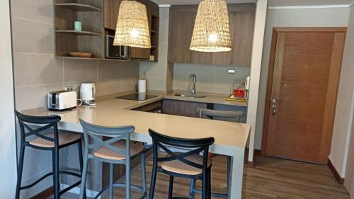 a kitchen with a counter with chairs and a table at Nuevo departamento con estacionamiento y a pasos del centro de Puerto Varas in Puerto Varas