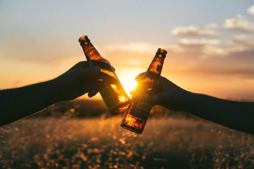 two people holding beer bottles in front of the sunset at Family-friendly Home on Boyd Lake, Gorgeous Views! in Loveland