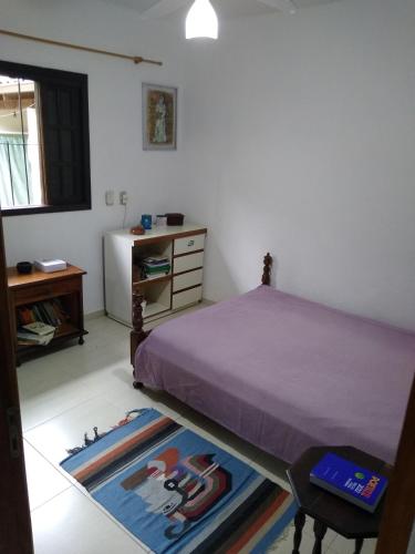 1 dormitorio con cama, escritorio y alfombra en Ótima localização em Ubatuba, en Ubatuba