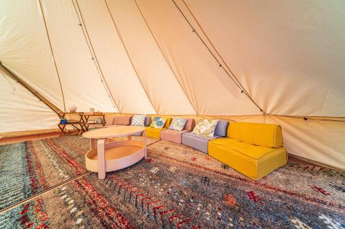 OKAYAMA GLAMPING SORANIA - Vacation STAY 73233v في كوراشيكي: غرفة معيشة مع أريكة وطاولات في خيمة