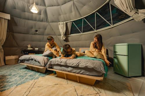 倉敷的住宿－OKAYAMA GLAMPING SORANIA - Vacation STAY 73195v，三个妇女坐在帐篷里的床上