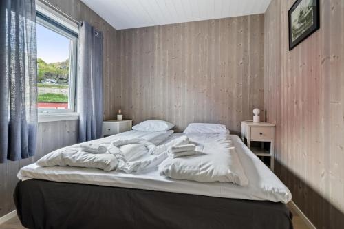 1 dormitorio con 1 cama con sábanas blancas y ventana en Finnvika Lodges, en Stamsund
