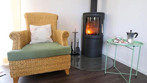 a wicker chair and a fireplace in a room at Urlaub am Kinispa in Hannersdorf