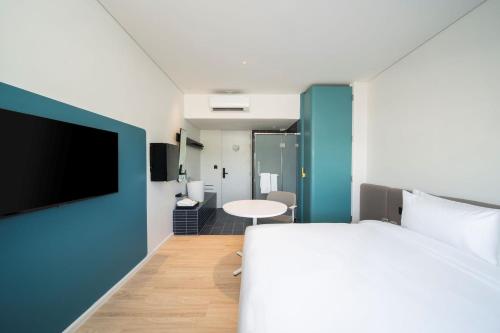 a bedroom with a bed and a table and a tv at GO Hotel Bowin at Robinson Lifestyle Bowin in Si Racha