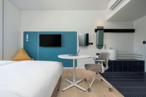 a bedroom with a bed and a table and chairs at GO Hotel Bowin at Robinson Lifestyle Bowin in Si Racha