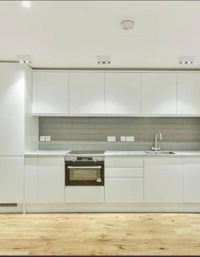 uma cozinha branca com armários brancos e um lavatório em Apartment Zone 1 Monument em Londres