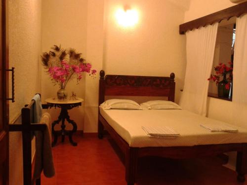 a bedroom with two beds and a table with flowers at Afonso Guest House in Panaji
