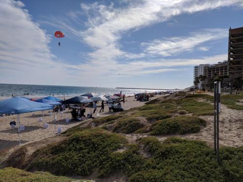 a beach with umbrellas and a kite in the sky at Bella Sirena Beauty 201-C - Stunning Views & Beachfront Bliss in Puerto Peñasco