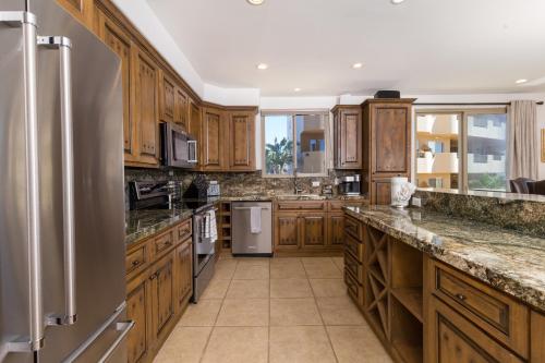 a large kitchen with wooden cabinets and stainless steel appliances at Bella Sirena Beauty 201-C - Stunning Views & Beachfront Bliss in Puerto Peñasco