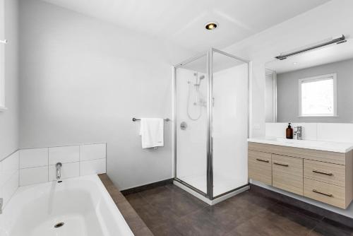 a white bathroom with a tub and a shower at Village House - 2-min walk into Havelock in Havelock North