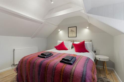 Dillywicks by Staytor Accommodation في إكسيتير: غرفة نوم بسرير كبير ومخدات حمراء