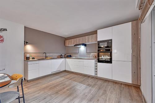 a kitchen with white cabinets and a wooden floor at Aux MARCHES DU PALAIS - AC CLIM - SPACIEUX - TERRASSE - WIFI in Avignon